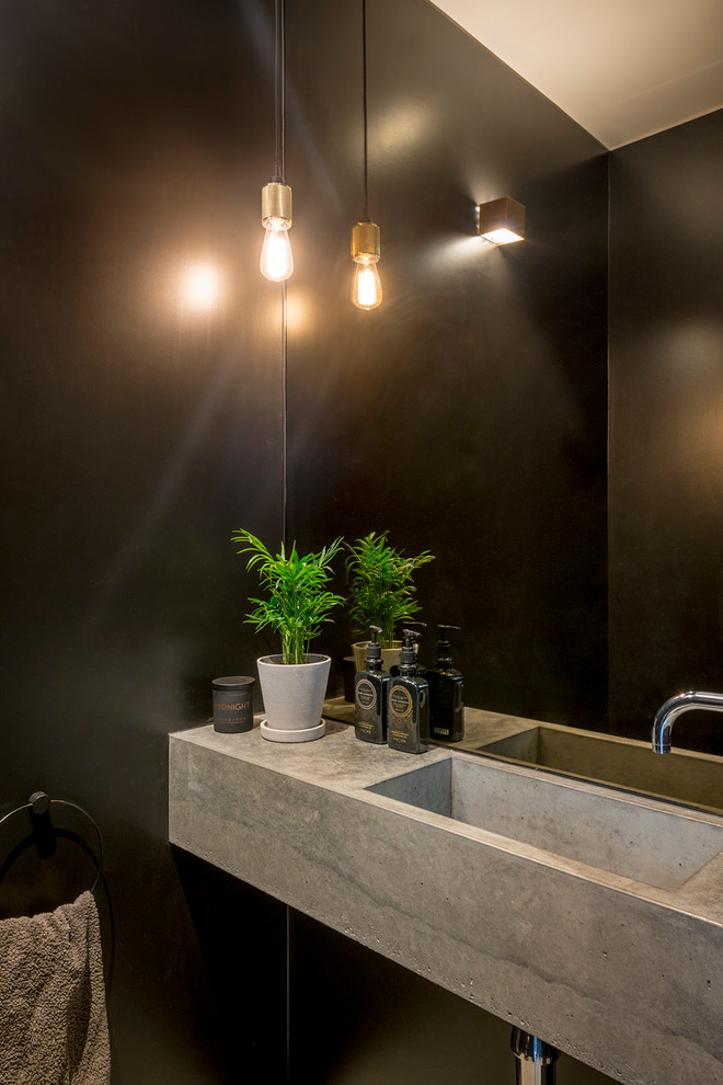 ロンドンにある高級な小さなインダストリアルスタイルのおしゃれなトイレ・洗面所 (壁掛け式トイレ、黒いタイル、ミラータイル、黒い壁、コンクリートの床、コンソール型シンク、コンクリートの洗面台、グレーの床) の写真