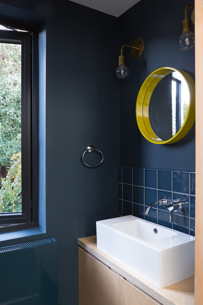 Idee per un bagno di servizio design con ante lisce, piastrelle blu, piastrelle in ceramica, pareti blu, lavabo a bacinella, top in legno, top beige e ante in legno chiaro