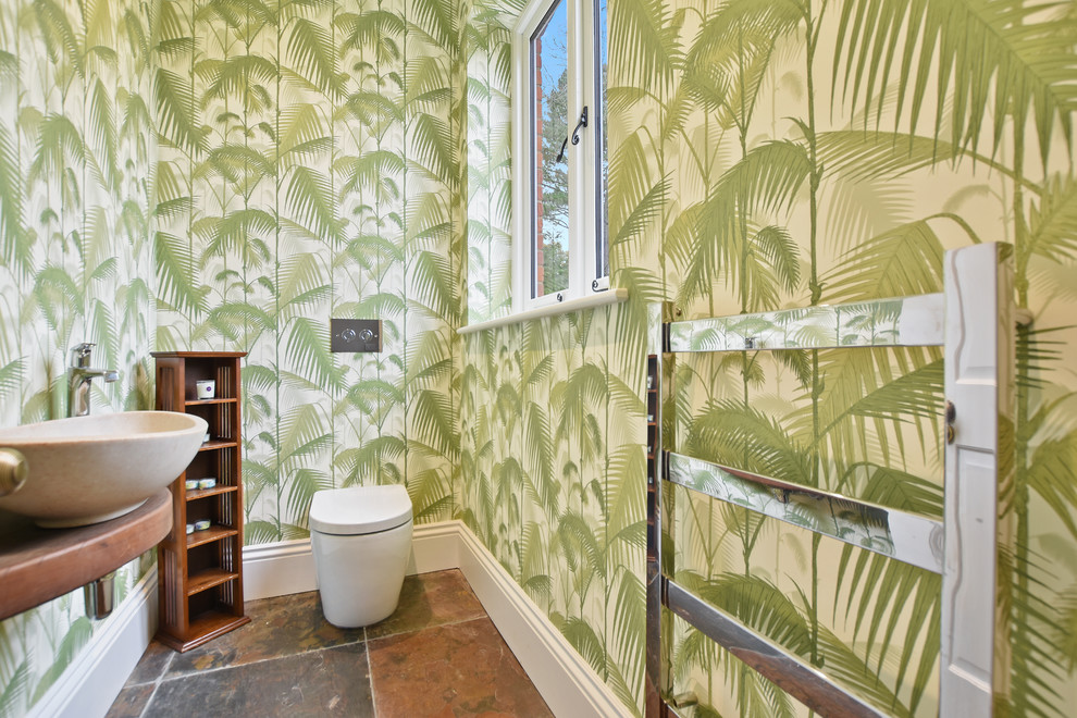 Imagen de aseo tropical de tamaño medio con sanitario de una pieza, lavabo sobreencimera y suelo marrón