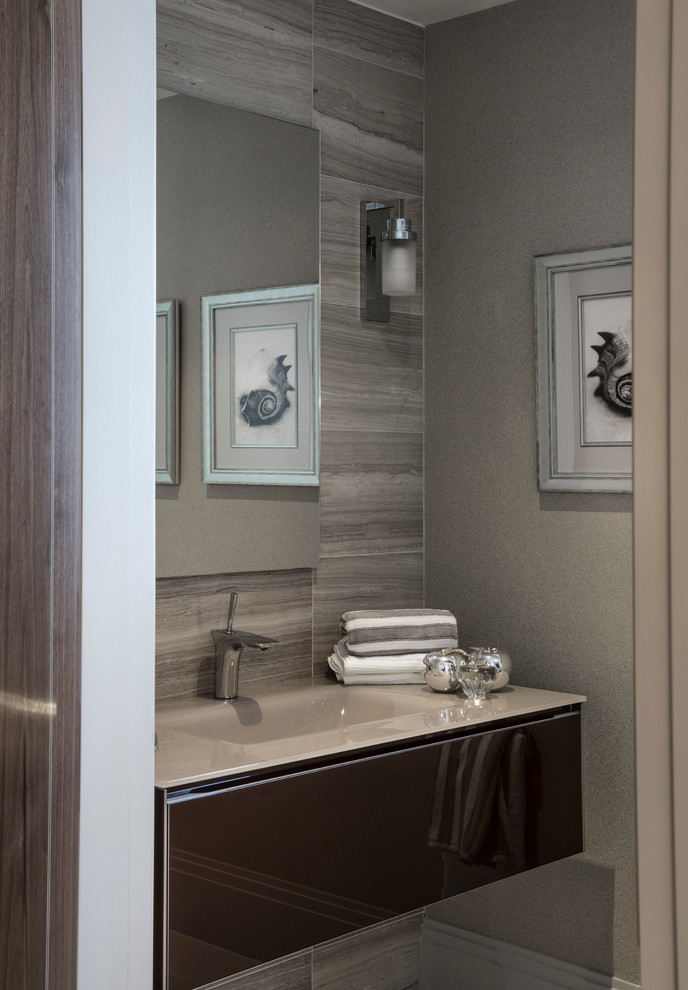 Design ideas for a medium sized contemporary cloakroom in London with glass-front cabinets, brown cabinets, glass worktops, grey tiles, grey walls, stone tiles and an integrated sink.