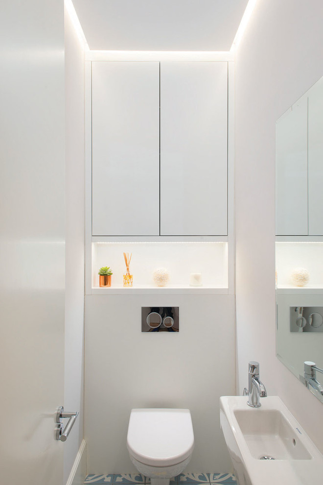 Photo of a small contemporary cloakroom in London with flat-panel cabinets, white cabinets, a one-piece toilet, white walls and a wall-mounted sink.