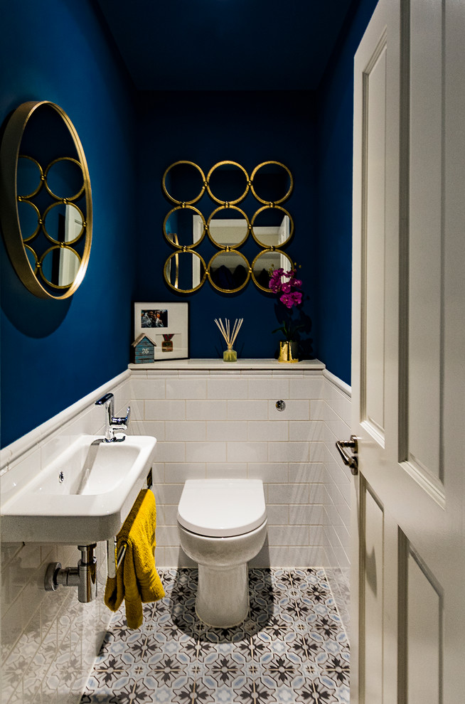Idéer för ett modernt toalett, med en toalettstol med hel cisternkåpa, vit kakel, blå väggar, cementgolv, ett väggmonterat handfat och flerfärgat golv