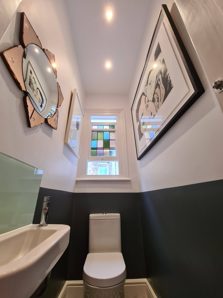 Photo of a medium sized modern cloakroom in London with freestanding cabinets, white cabinets, a two-piece toilet, porcelain tiles, white walls, porcelain flooring, a wall-mounted sink, beige floors, a freestanding vanity unit and a drop ceiling.