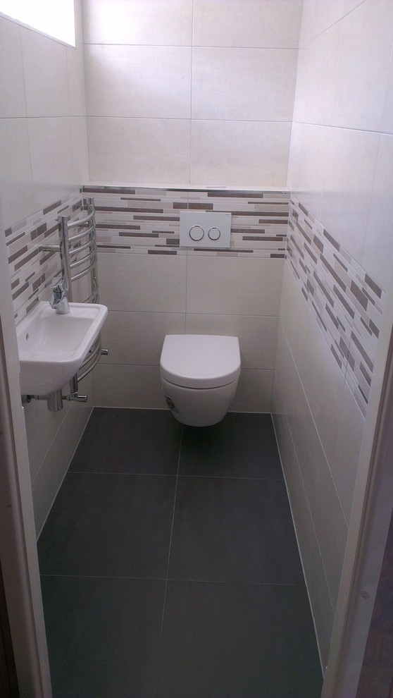 Inspiration for a small modern cloakroom in West Midlands with a wall mounted toilet, multi-coloured tiles, ceramic tiles, a wall-mounted sink and white walls.