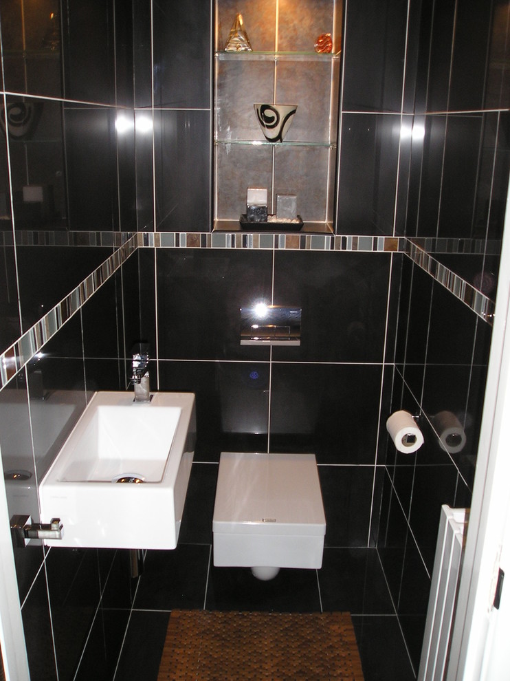 Ispirazione per un piccolo bagno di servizio minimalista con WC sospeso, piastrelle nere, piastrelle in gres porcellanato, pareti nere, pavimento in gres porcellanato e lavabo sospeso