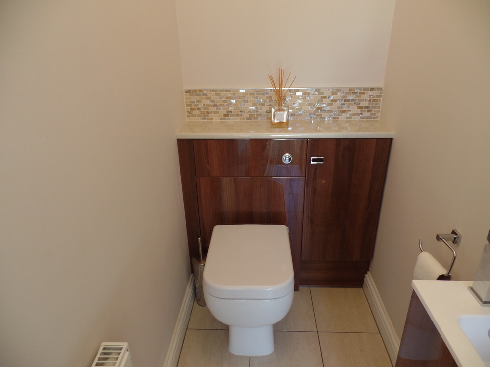 Cette photo montre un petit WC et toilettes moderne avec un placard à porte plane, un plan de toilette en stratifié, un mur beige et mosaïque.