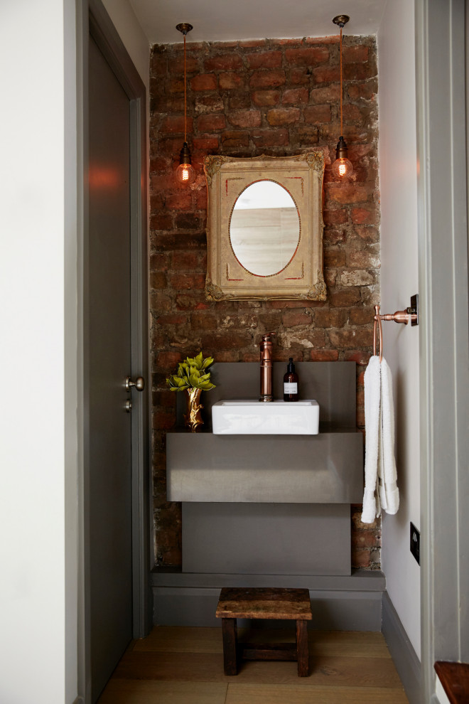 На фото: туалет в стиле фьюжн с светлым паркетным полом и кирпичными стенами с