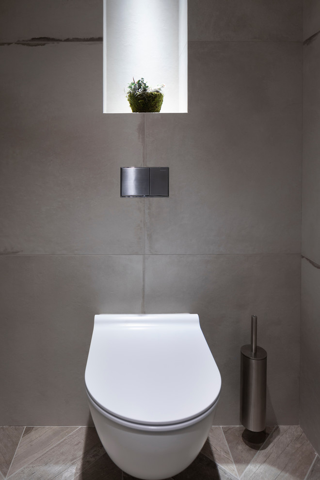 Idées déco pour un WC suspendu contemporain de taille moyenne avec un carrelage gris, des carreaux de porcelaine, un mur gris, un sol en carrelage de porcelaine, une grande vasque, un plan de toilette en carrelage, un sol gris et un plan de toilette gris.
