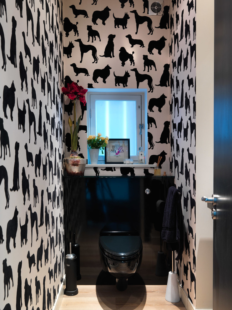 Kleine Moderne Gästetoilette mit flächenbündigen Schrankfronten, schwarzen Schränken, bunten Wänden, hellem Holzboden und Wandtoilette in London
