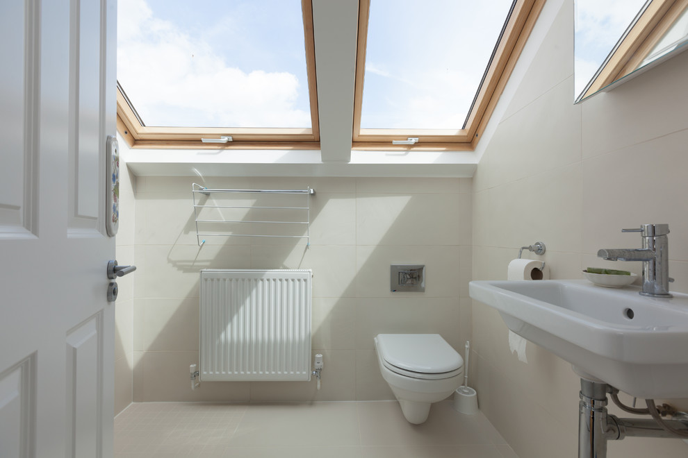 На фото: туалет в современном стиле с инсталляцией, бежевой плиткой, бежевыми стенами, подвесной раковиной и бежевым полом с