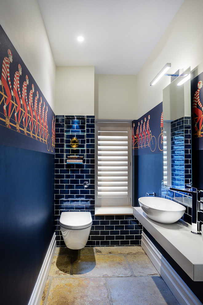 Inspiration for an eclectic cloakroom in Hampshire with blue tiles, blue walls, limestone flooring, brown floors, a wall mounted toilet, metro tiles, a vessel sink and grey worktops.