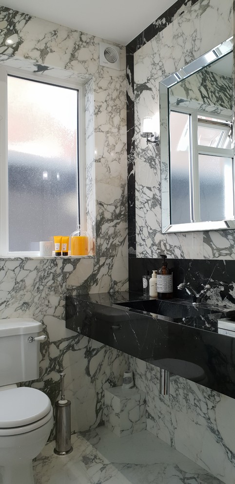 Example of a small trendy white tile and marble tile marble floor and white floor powder room design in London with open cabinets, a two-piece toilet, white walls, a drop-in sink and marble countertops