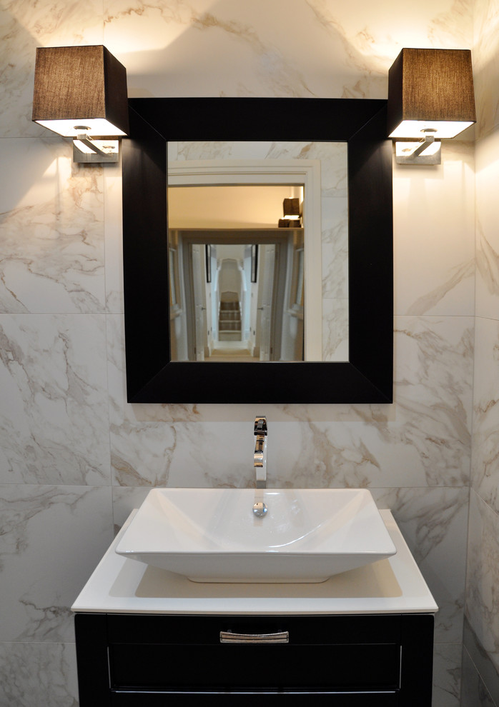 Small contemporary cloakroom in London with a vessel sink, freestanding cabinets, dark wood cabinets, solid surface worktops, a wall mounted toilet, ceramic tiles, multi-coloured walls and white tiles.