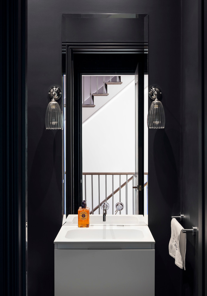 Powder room - small contemporary powder room idea in London with flat-panel cabinets, white cabinets, black walls and a wall-mount sink