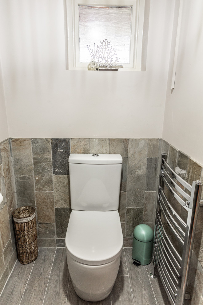 Cette photo montre un petit WC et toilettes tendance avec un placard à porte plane, des portes de placard grises, un carrelage multicolore, un sol en carrelage de céramique et un sol marron.