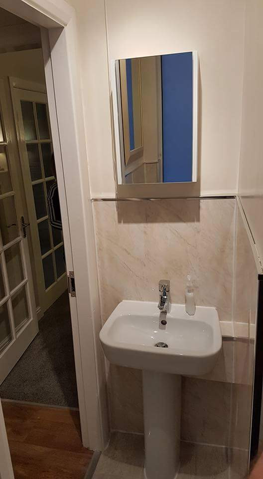Cette photo montre un petit WC et toilettes méditerranéen avec WC à poser, un carrelage beige, du carrelage en travertin, un mur blanc, un sol en vinyl, un lavabo de ferme, un sol gris, meuble-lavabo sur pied et du lambris.