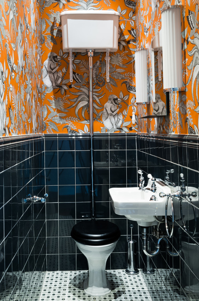 Klassisk inredning av ett mellanstort toalett, med en toalettstol med separat cisternkåpa, svart kakel, porslinskakel, klinkergolv i porslin, ett väggmonterat handfat, flerfärgade väggar och flerfärgat golv