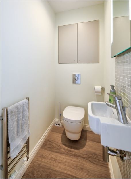 Modelo de aseo contemporáneo pequeño con sanitario de pared, baldosas y/o azulejos grises, baldosas y/o azulejos en mosaico, paredes blancas, suelo de madera en tonos medios y lavabo suspendido