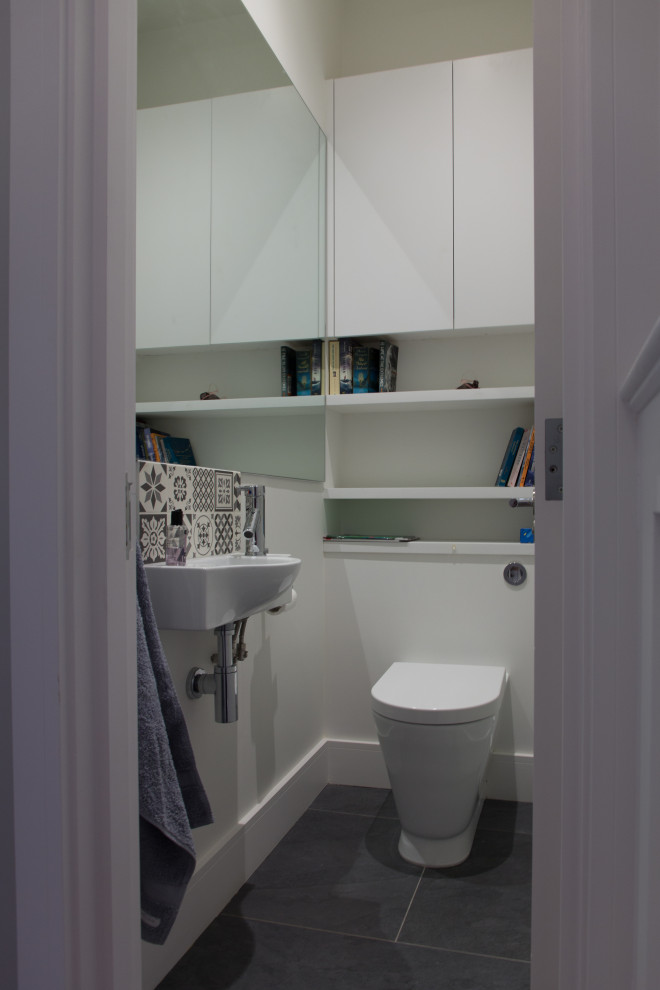 Foto på ett litet funkis toalett, med en vägghängd toalettstol, flerfärgad kakel, perrakottakakel, vita väggar, klinkergolv i porslin, ett väggmonterat handfat och grått golv