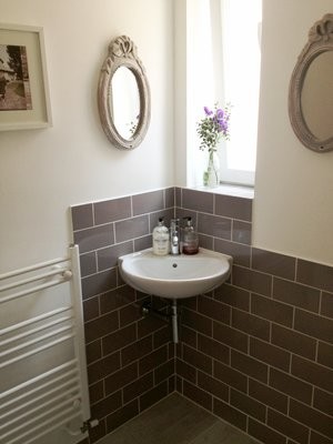 Immagine di un bagno di servizio moderno con ante in stile shaker, ante bianche, WC sospeso, piastrelle grigie, piastrelle in ceramica, pareti grigie, pavimento con piastrelle in ceramica, lavabo sospeso e pavimento bianco