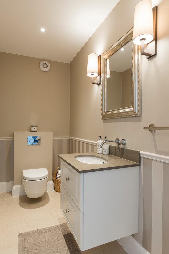 Inspiration pour un petit WC suspendu traditionnel avec un placard à porte shaker, des portes de placard blanches, un mur beige, un sol en carrelage de porcelaine, un lavabo encastré, un plan de toilette en surface solide, un sol beige et un plan de toilette marron.