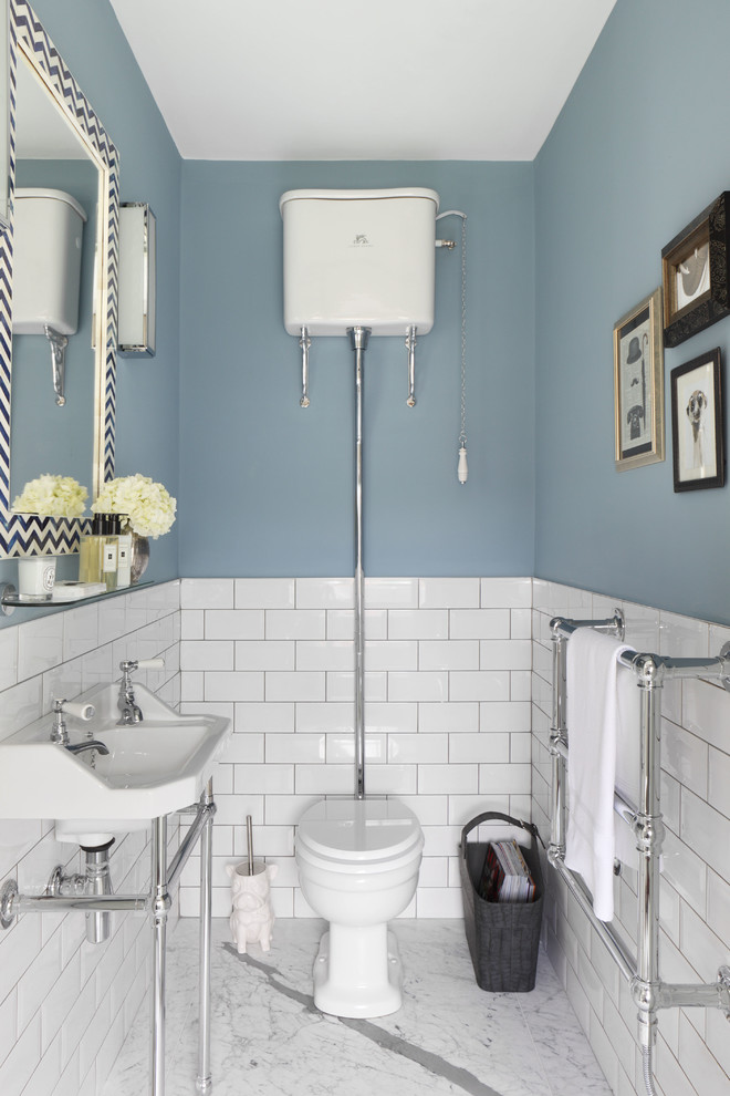 Inspiration för små klassiska toaletter, med en toalettstol med separat cisternkåpa, vit kakel, blå väggar, marmorgolv, tunnelbanekakel och ett konsol handfat