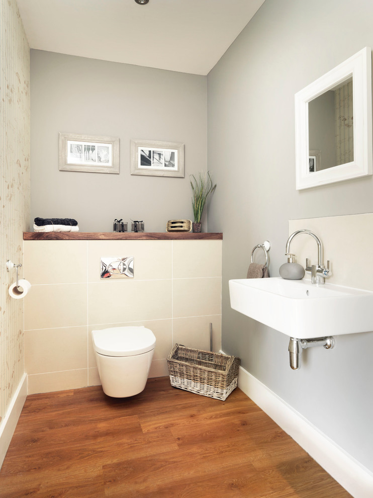 Powder room - small coastal beige tile and ceramic tile medium tone wood floor powder room idea in Hampshire with a wall-mount toilet, gray walls and a wall-mount sink