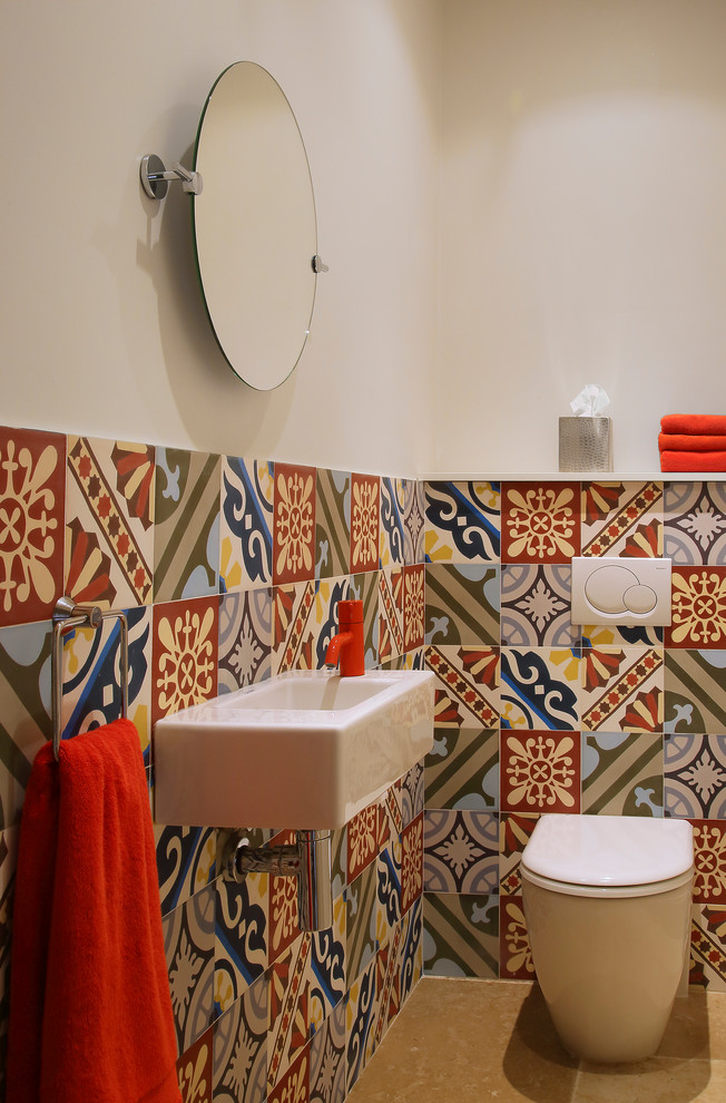 Modelo de aseo mediterráneo pequeño con lavabo suspendido, baldosas y/o azulejos multicolor, paredes multicolor, suelo de baldosas de porcelana y sanitario de una pieza