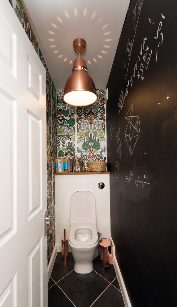 ロンドンにある小さなコンテンポラリースタイルのおしゃれなトイレ・洗面所 (一体型トイレ	、黒いタイル、マルチカラーの壁、セラミックタイルの床) の写真