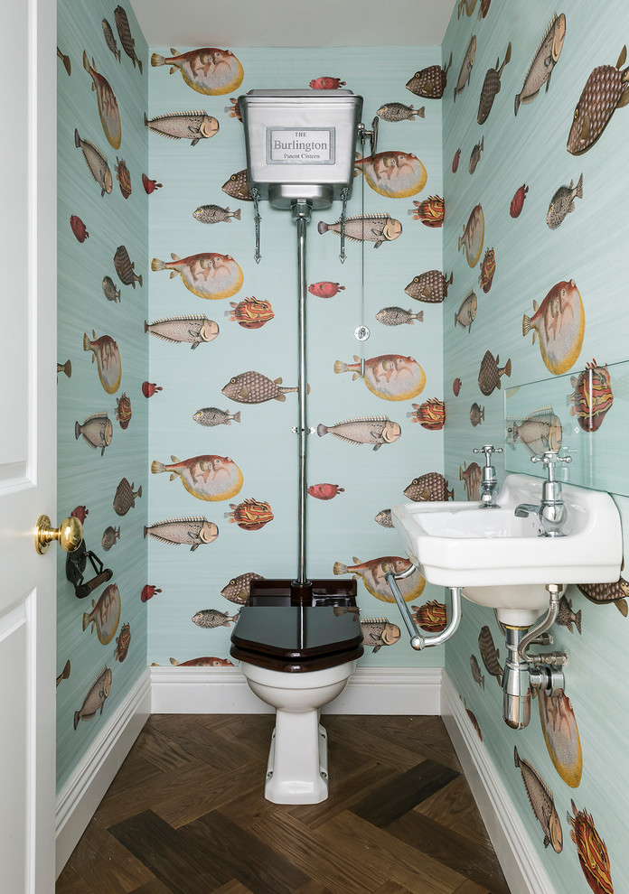 Photo of a coastal cloakroom in London with a wall-mounted sink, a two-piece toilet, multi-coloured walls and dark hardwood flooring.