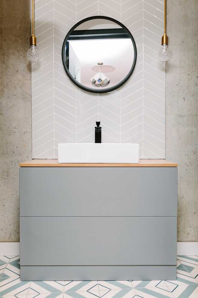 На фото: туалет в современном стиле с плоскими фасадами, серыми фасадами, серой плиткой, серыми стенами, настольной раковиной и разноцветным полом
