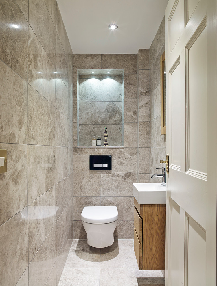 Exempel på ett modernt toalett, med släta luckor, skåp i ljust trä, travertin golv, grå kakel och ett fristående handfat