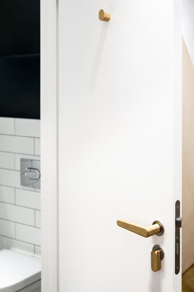 This is an example of a small traditional cloakroom in London with white tiles, flat-panel cabinets, light wood cabinets, a wall mounted toilet, metro tiles, grey walls, ceramic flooring, an integrated sink, wooden worktops and grey floors.
