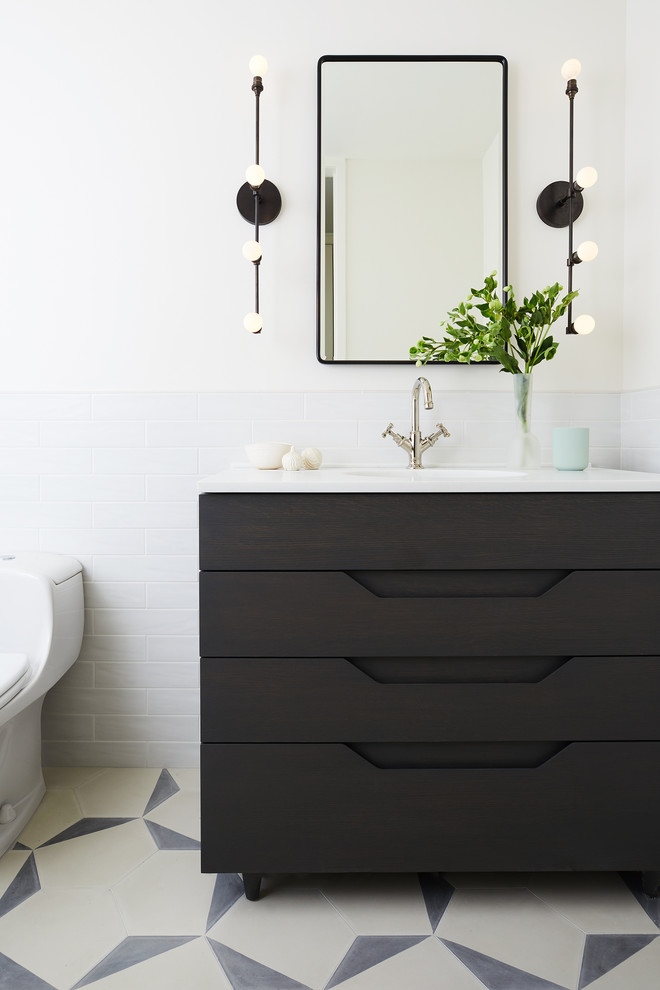 Foto på ett skandinaviskt vit toalett, med möbel-liknande, svarta skåp, vita väggar och flerfärgat golv
