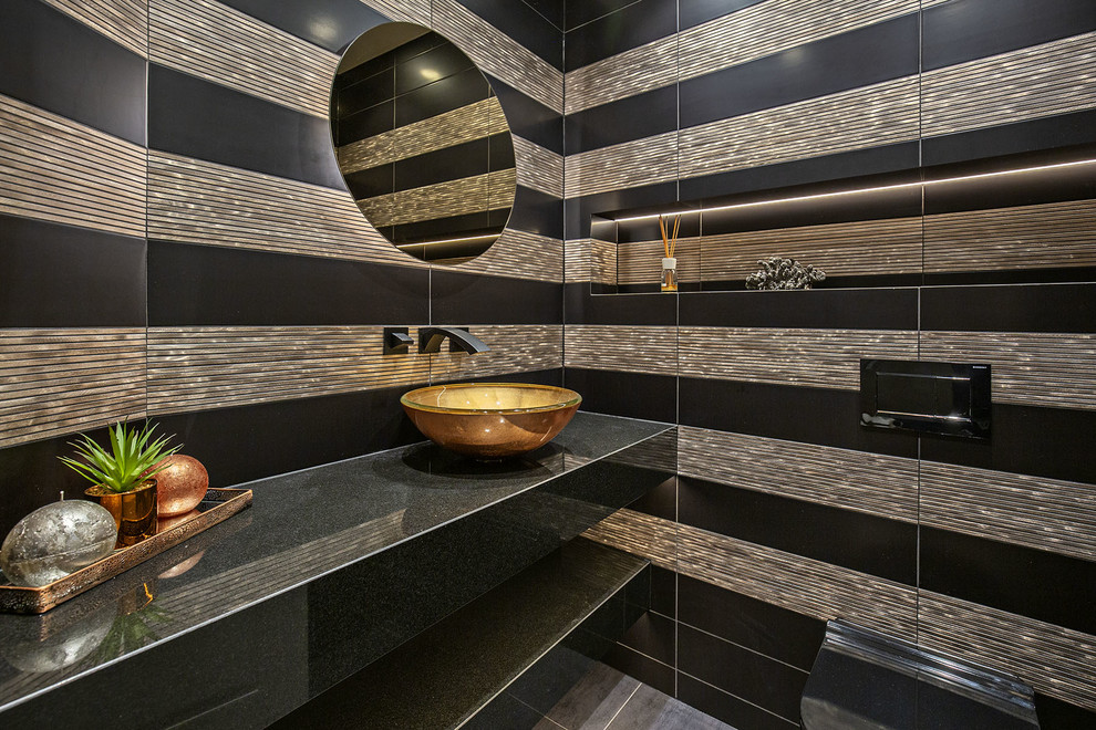 Example of a mid-sized trendy multicolored tile and porcelain tile porcelain tile and black floor powder room design in London with a one-piece toilet, multicolored walls, a wall-mount sink, granite countertops and black countertops
