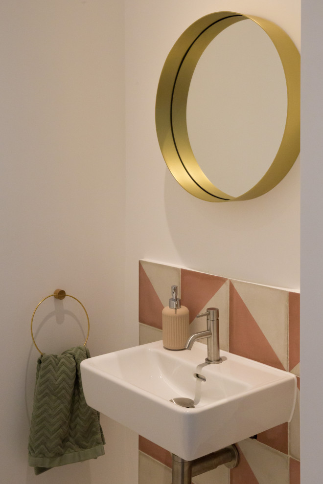This is an example of a contemporary cloakroom in London with pink tiles and a wall-mounted sink.