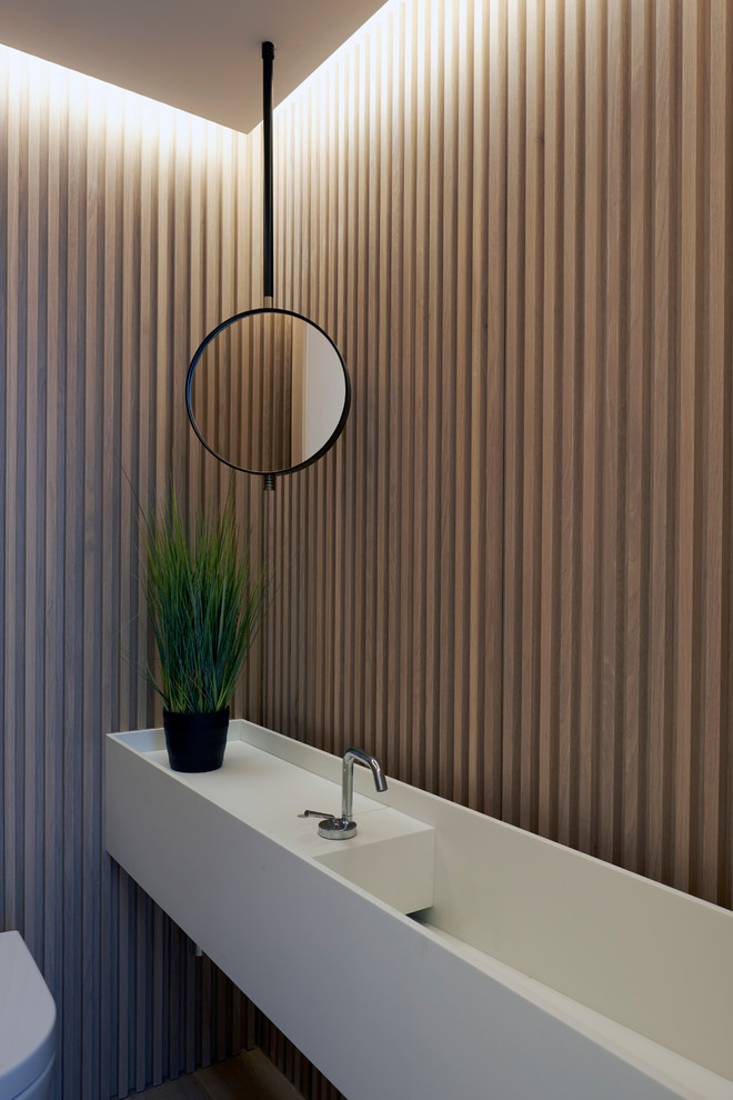 Idée de décoration pour un WC et toilettes design avec un mur marron et un lavabo intégré.