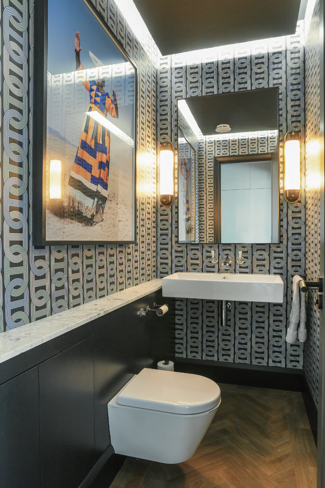 ロンドンにあるコンテンポラリースタイルのおしゃれなトイレ・洗面所 (壁掛け式トイレ、マルチカラーの壁、無垢フローリング、壁付け型シンク、茶色い床) の写真