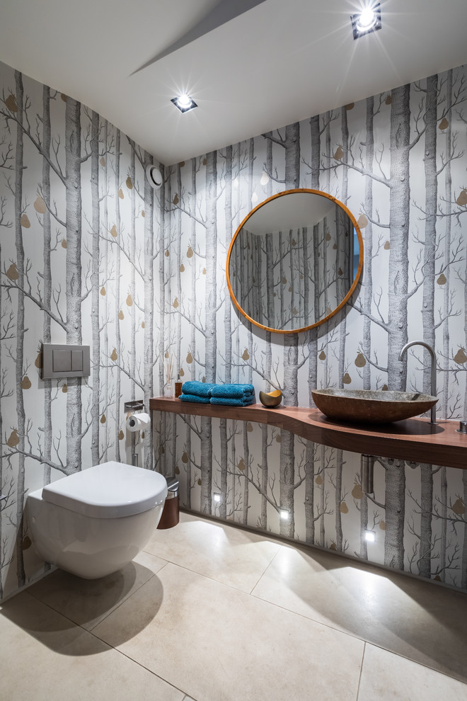 Пример оригинального дизайна: туалет в современном стиле с разноцветными стенами, настольной раковиной, столешницей из дерева, бежевым полом и коричневой столешницей