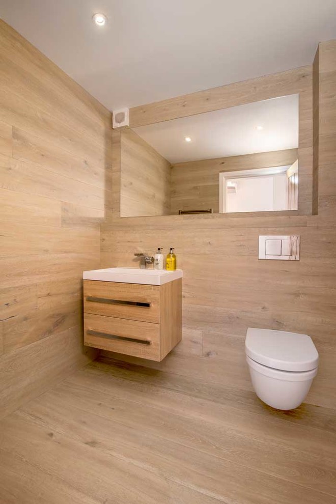 Inspiration pour un WC suspendu design en bois clair avec un placard à porte plane, parquet clair et un sol beige.