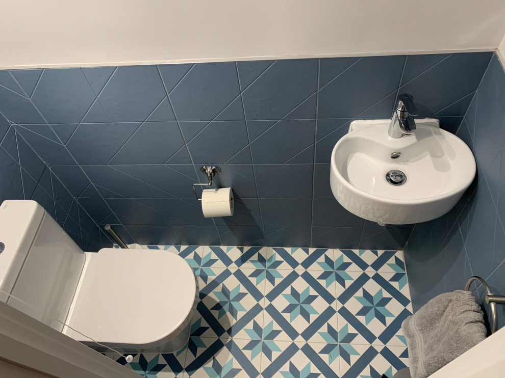 На фото: маленький туалет в стиле модернизм с унитазом-моноблоком, синей плиткой, серыми стенами, полом из керамической плитки, подвесной раковиной и разноцветным полом для на участке и в саду