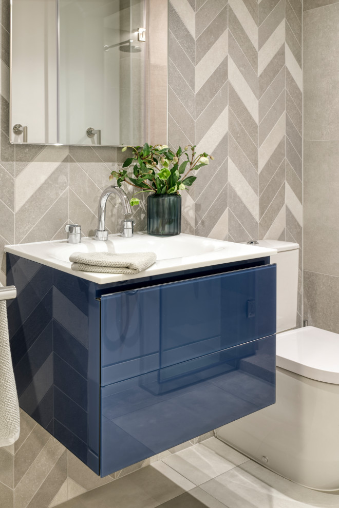 Small contemporary cloakroom in London with flat-panel cabinets, blue cabinets, a two-piece toilet, grey tiles, limestone tiles, grey walls, marble flooring, a wall-mounted sink, white floors, white worktops and a floating vanity unit.