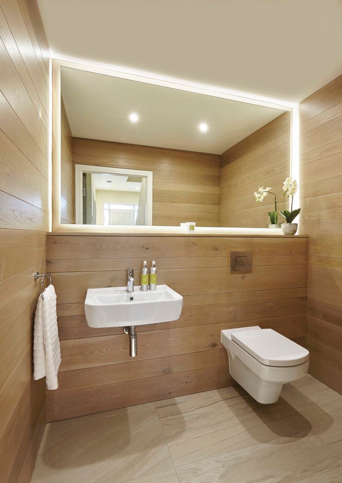 Diseño de aseo actual con sanitario de pared, paredes marrones, lavabo suspendido y suelo beige