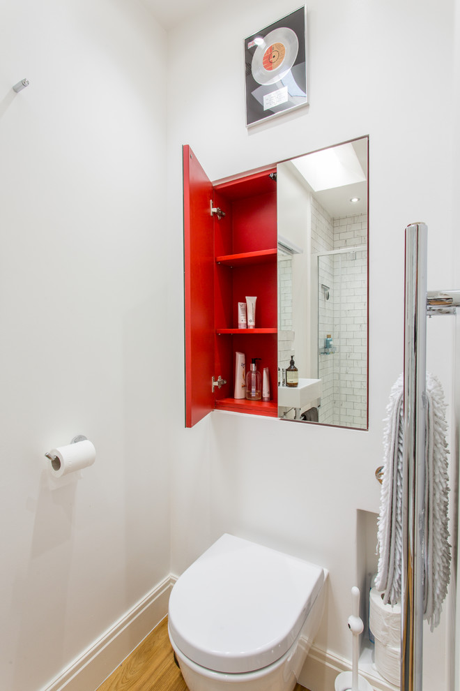 Kleine Moderne Gästetoilette mit Wandtoilette, weißer Wandfarbe und braunem Holzboden in Sonstige