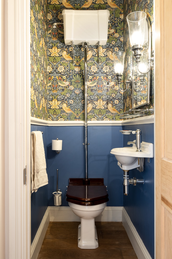 Diseño de aseo escandinavo, pequeño, con sanitario de dos piezas, suelo de madera en tonos medios, lavabo suspendido, suelo marrón y paredes multicolor