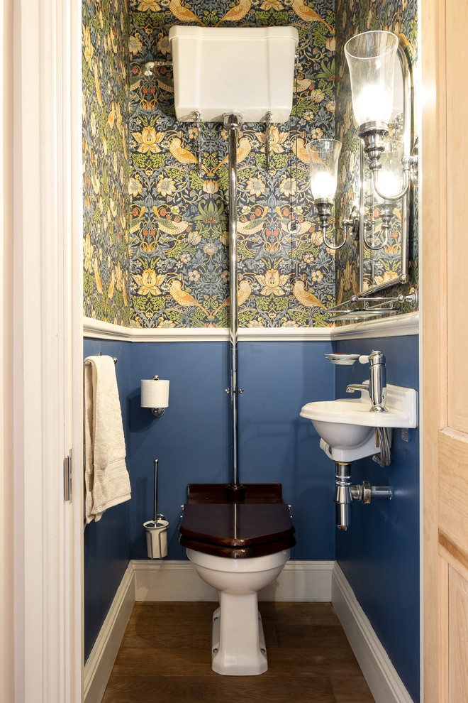 Idee per un piccolo bagno di servizio nordico con WC a due pezzi, pavimento in legno massello medio, lavabo sospeso, pavimento marrone e pareti multicolore