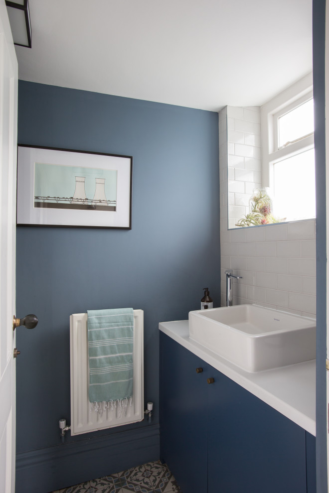 Design ideas for a small contemporary cloakroom in Other with flat-panel cabinets, blue cabinets, white tiles, metro tiles, blue walls, a vessel sink, multi-coloured floors, white worktops and a built in vanity unit.