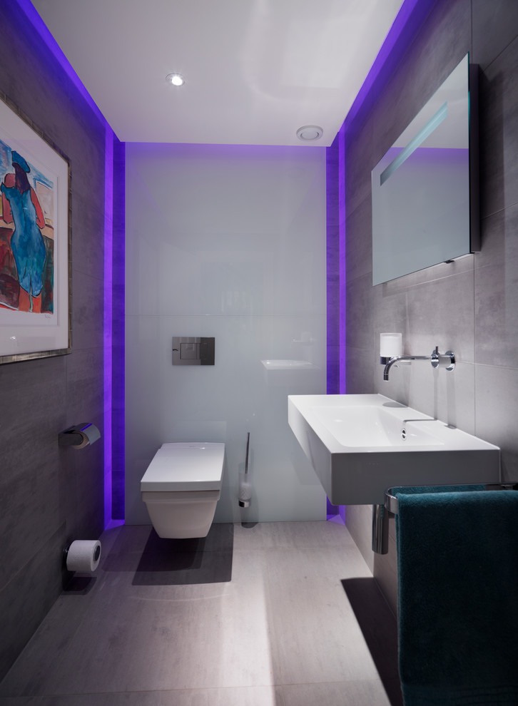 Inspiration for a mid-sized contemporary gray tile and porcelain tile porcelain tile powder room remodel in Wiltshire with a wall-mount toilet, gray walls and a wall-mount sink