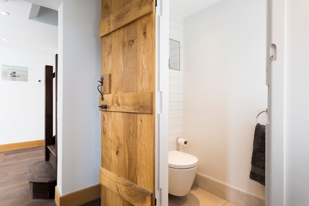 Exempel på ett litet rustikt toalett, med öppna hyllor, en vägghängd toalettstol, vit kakel, porslinskakel, vita väggar, klinkergolv i porslin, ett piedestal handfat och träbänkskiva