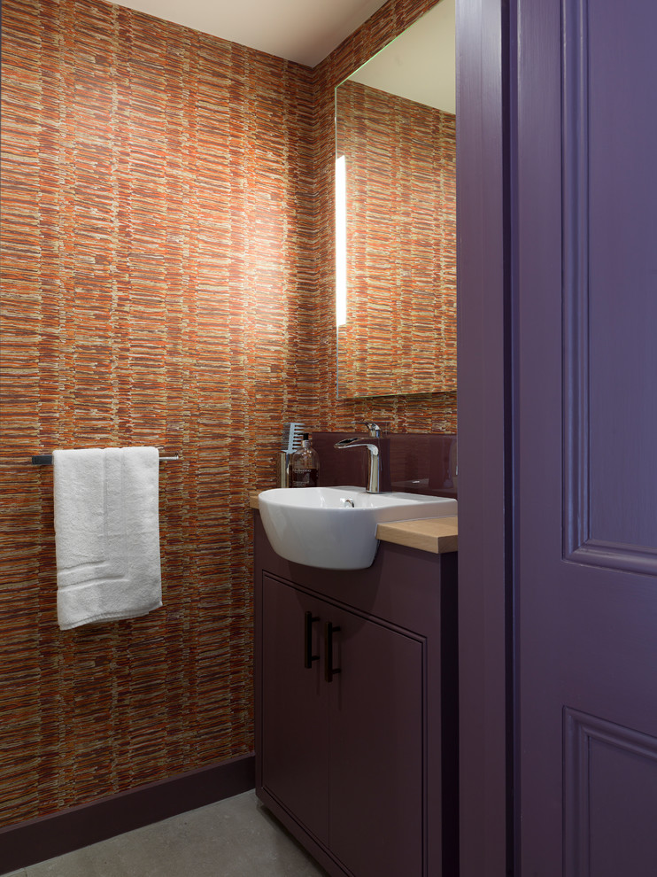 Foto di un bagno di servizio contemporaneo con ante lisce, ante viola, pareti arancioni, lavabo da incasso e top in legno